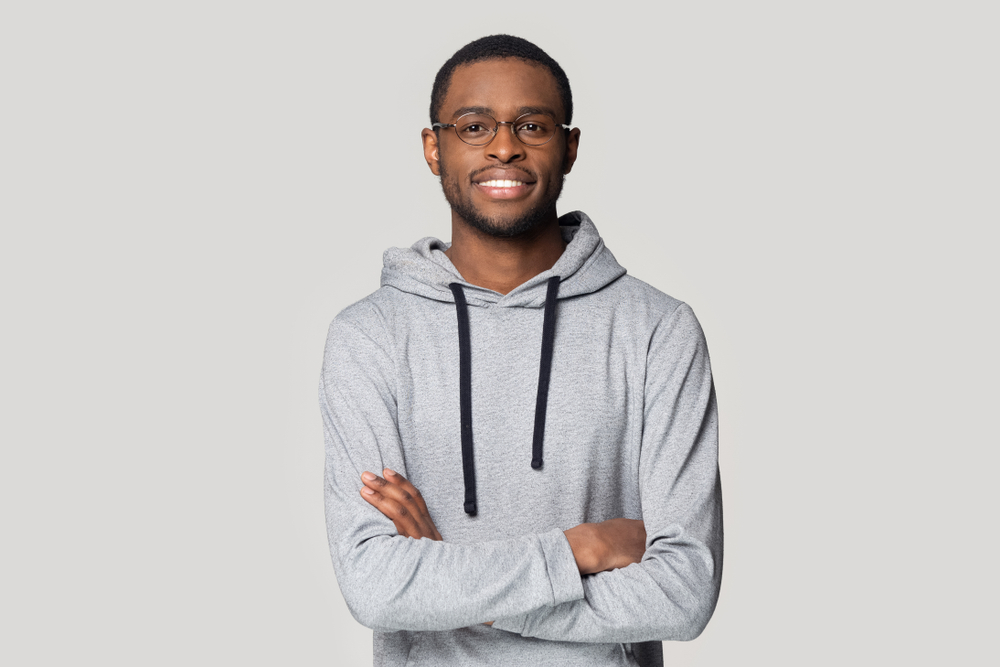 smiling african-american skinhead guy wearing eyeglasses and hoodie.