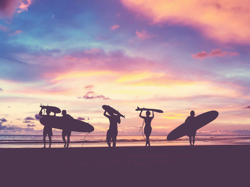 Silhouette Of surfer people carrying their surfboard on sunset beach, vintage filter effect with soft style 