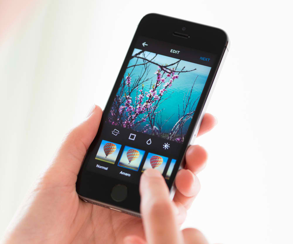 Person이 새로운 Apple iPhone 5S의 Instagram 애플리케이션에서 이미지에 디지털 필터를 적용합니다. Instagram은 2010년 10월에 출시된 모바일 소셜 네트워킹 서비스입니다.